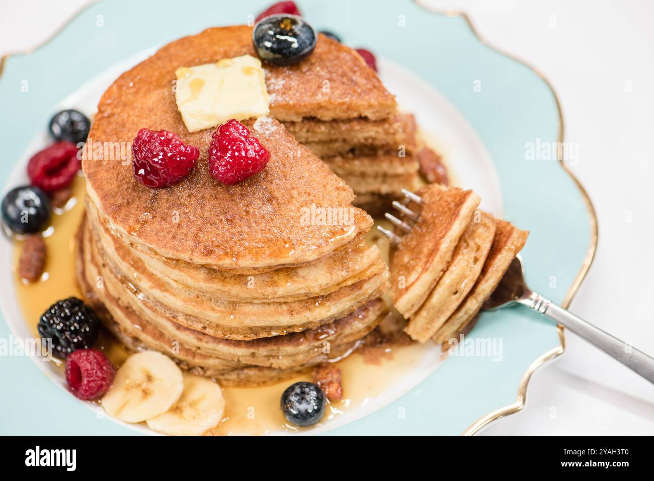 Una pila di pancake tagliati con una forchetta e frutti di bosco Foto Stock