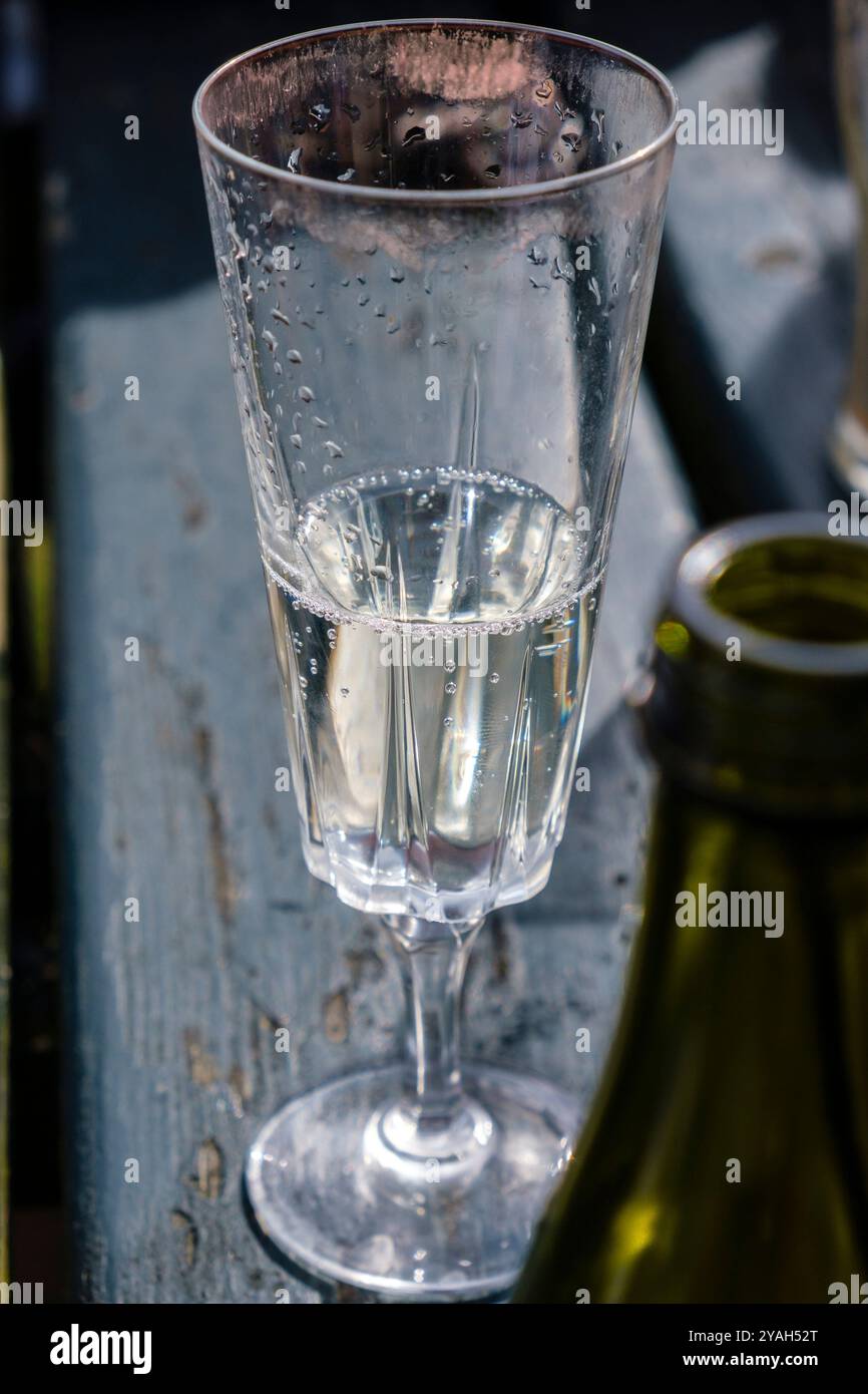 Un alto flauto in vetro con vino frizzante al tavolo dei poub in estate. Il vetro è macchiato con il rossetto rosso nella parte superiore. Foto Stock