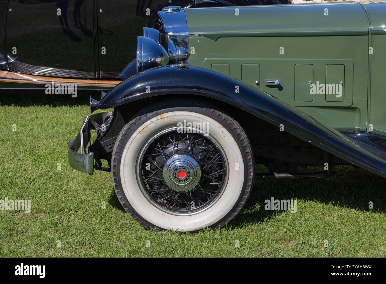 Primo piano della ruota a raggi di un'auto classica sull'erba, che mostra il suo design vintage e l'eleganza Foto Stock