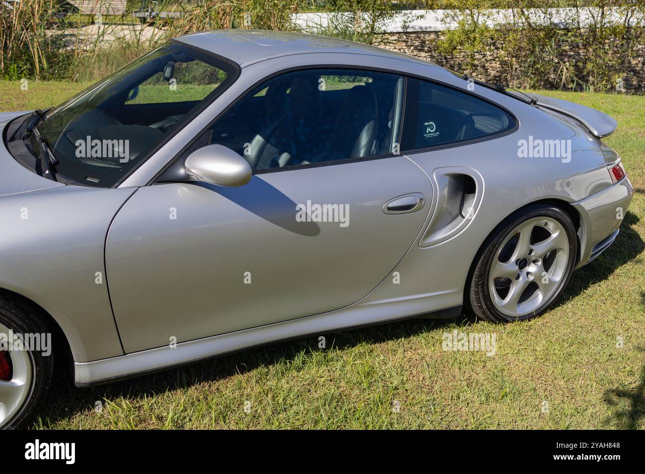 La porsche 911 Turbo color argento è parcheggiata su un campo erboso e mostra il suo design iconico e la sua presenza potente Foto Stock