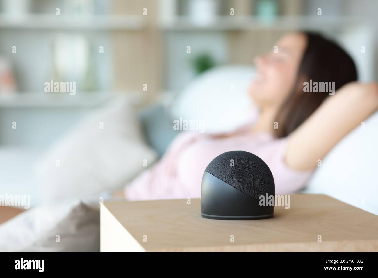 Visualizzazione laterale del ritratto di uno speaker intelligente con una donna rilassata sullo sfondo di casa Foto Stock