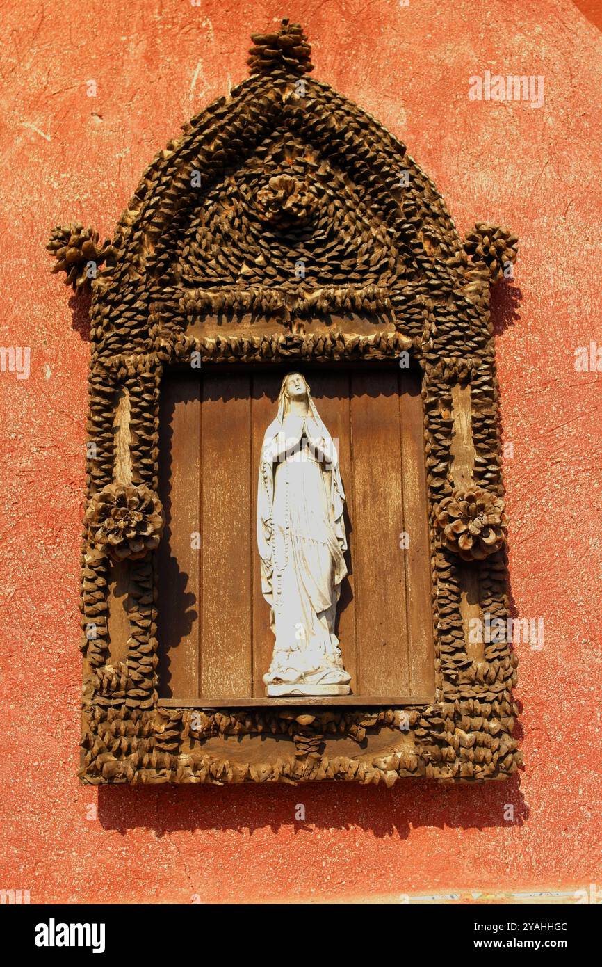 Sfondo rosso con statuetta della Madonna in preghiera Foto Stock