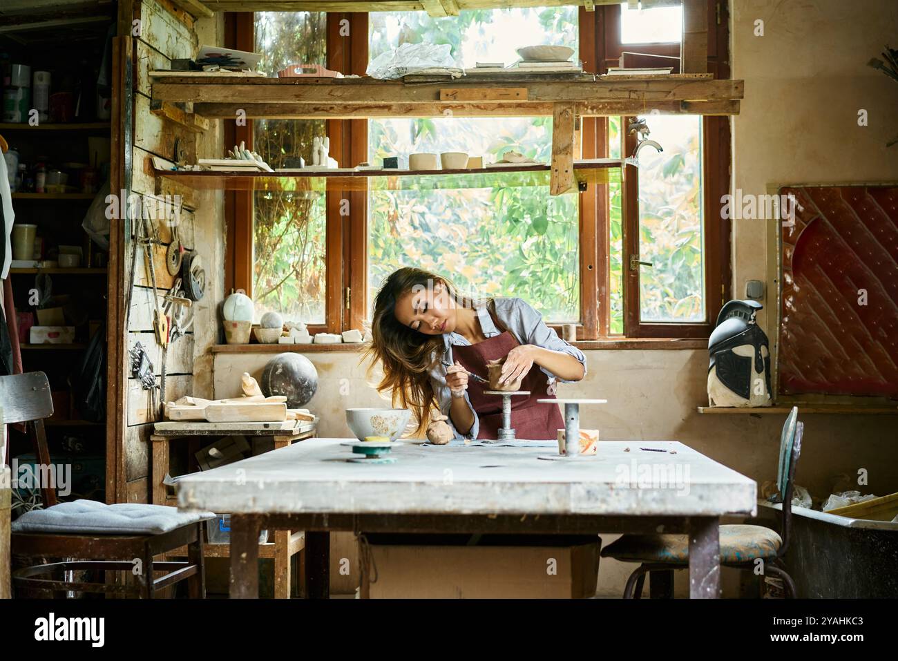 L'artista donna scolpisce i mestieri con l'argilla ceramica nel suo laboratorio creativo. Padroneggia l'arte della ceramica artigianale Foto Stock