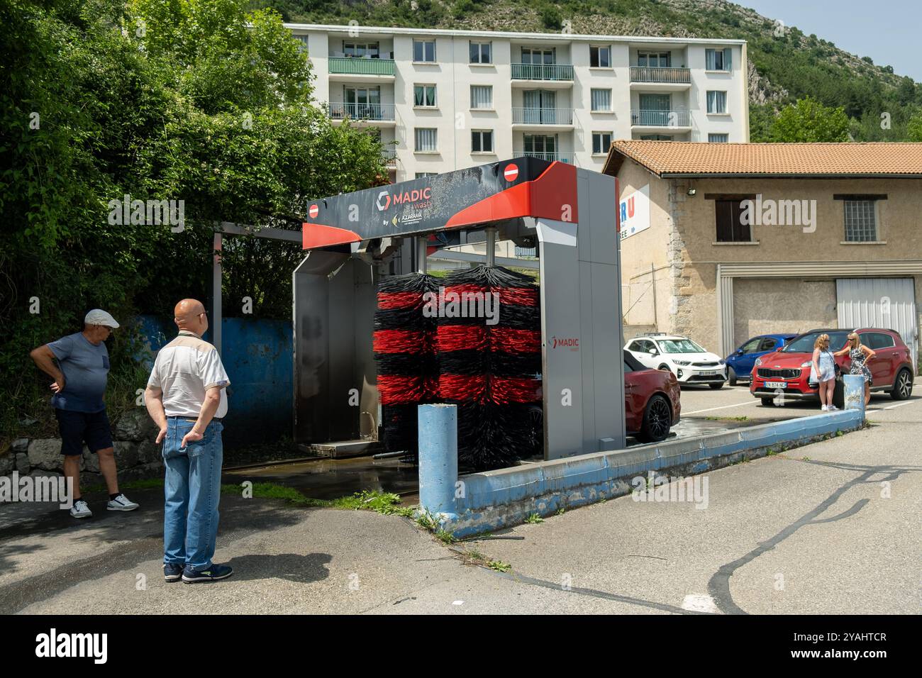 28.06.2024, Francia, Hautes-Alpes, Provence-Alpes-Cote d'Azur, Veynes - proprietario di un'auto sportiva rossa, autolavaggio nel villaggio delle Alpi. 00A240628D189CA Foto Stock