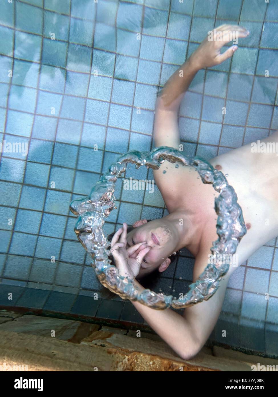 14.11.2023, Indonesia, Lombok, Gili Trawangan - il giovane uomo produce un anello d'aria sott'acqua nella piscina. 00S231114D429CAROEX.JPG [MODELLI RIPRESI Foto Stock