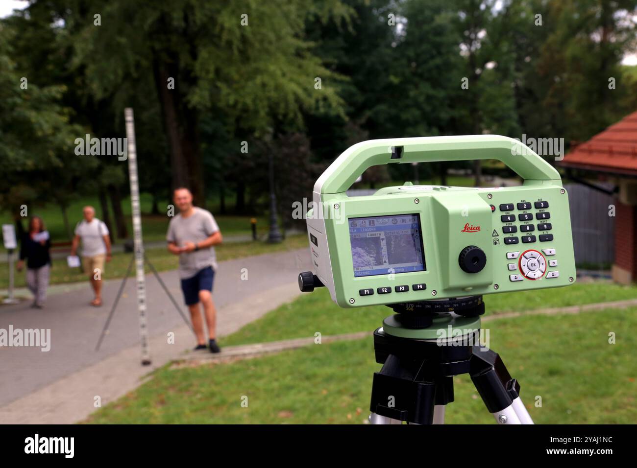 Cracovia. Cracovia. Polonia. Leica Digital Leica strumento di misurazione dell'altezza sul campo. Uomo con il personale visto in background fuori fuoco. Foto Stock