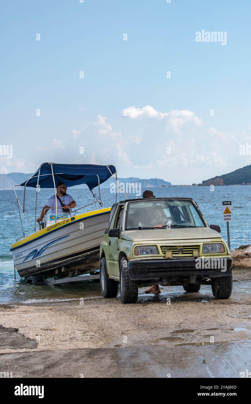 La barca viene lanciata su uno scalo pubblico utilizzando una piccola jeep Suzuki per abbassare gradualmente l'imbarcazione lungo il pendio fino al mare Foto Stock