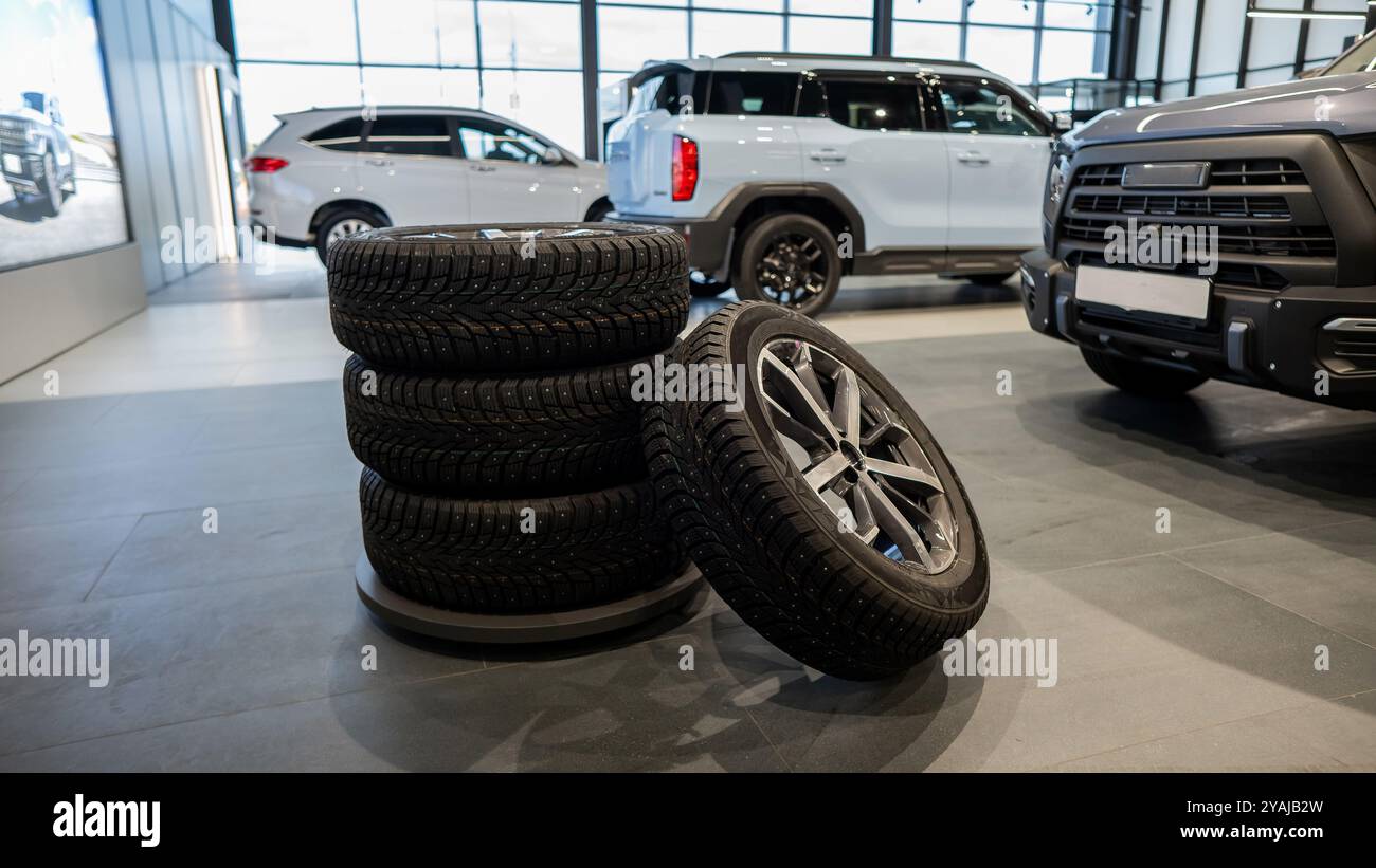 Nuovi cerchi con pneumatici chiodati sullo sfondo delle nuove auto. Foto Stock