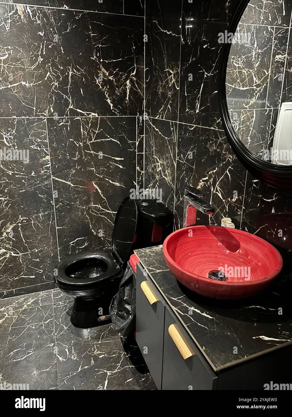 lavandino rosso in marmo nero - design strano - toilette scadente - bagno nero Foto Stock