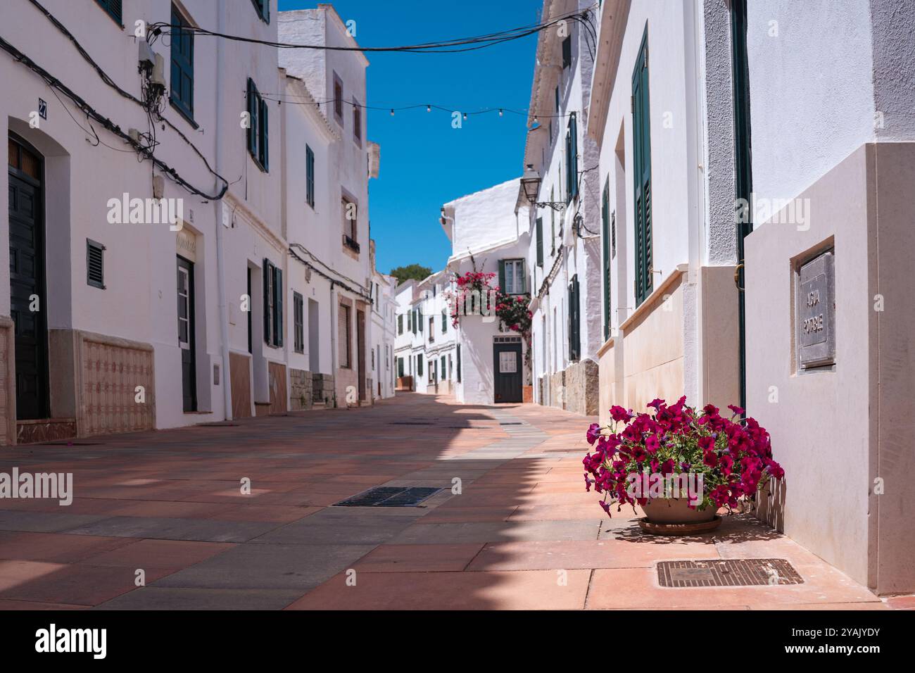 Vicolo tradizionale nella cittadina spagnola in una soleggiata giornata estiva con un cielo azzurro. Esempio di architettura classica di un villaggio in Spagna a Minorca Foto Stock