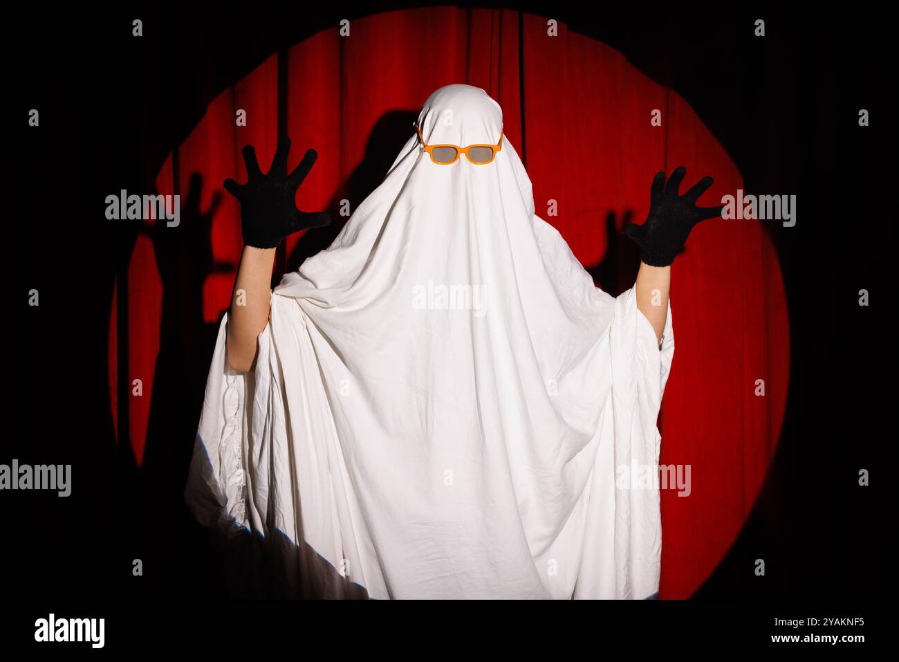 Uomo in costume bianco spaventoso fantasma su sfondo rosso, celebrazione di Halloween, concetto di Halloween Foto Stock