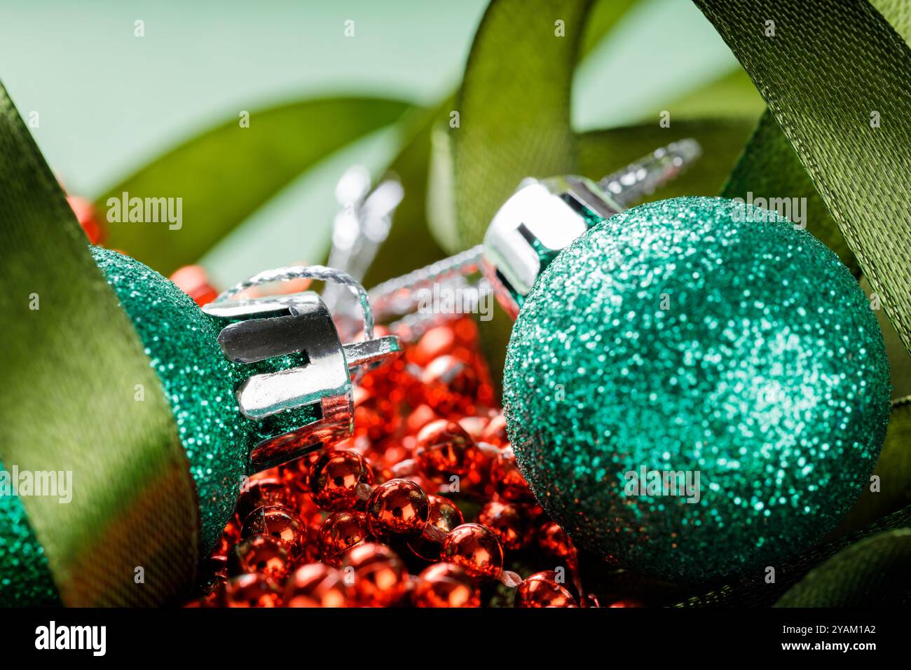 Decorazioni natalizie con palline di glitter verdi, perline rosse e nastro verde festivo, primo piano Foto Stock