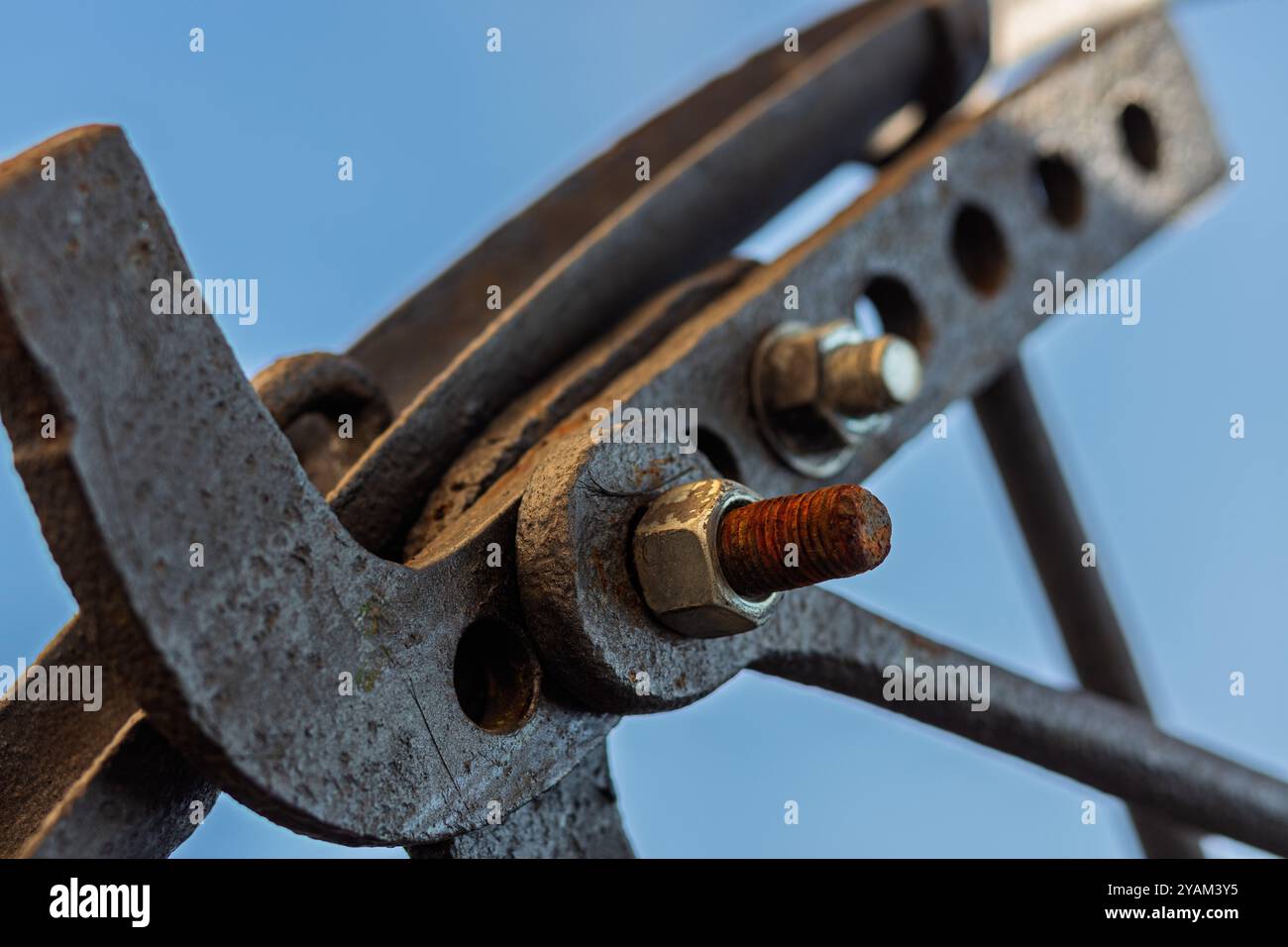 Morsetto in metallo arrugginito che fissa gli elementi di costruzione insieme a un collegamento filettato visibile e un cielo blu sullo sfondo Foto Stock