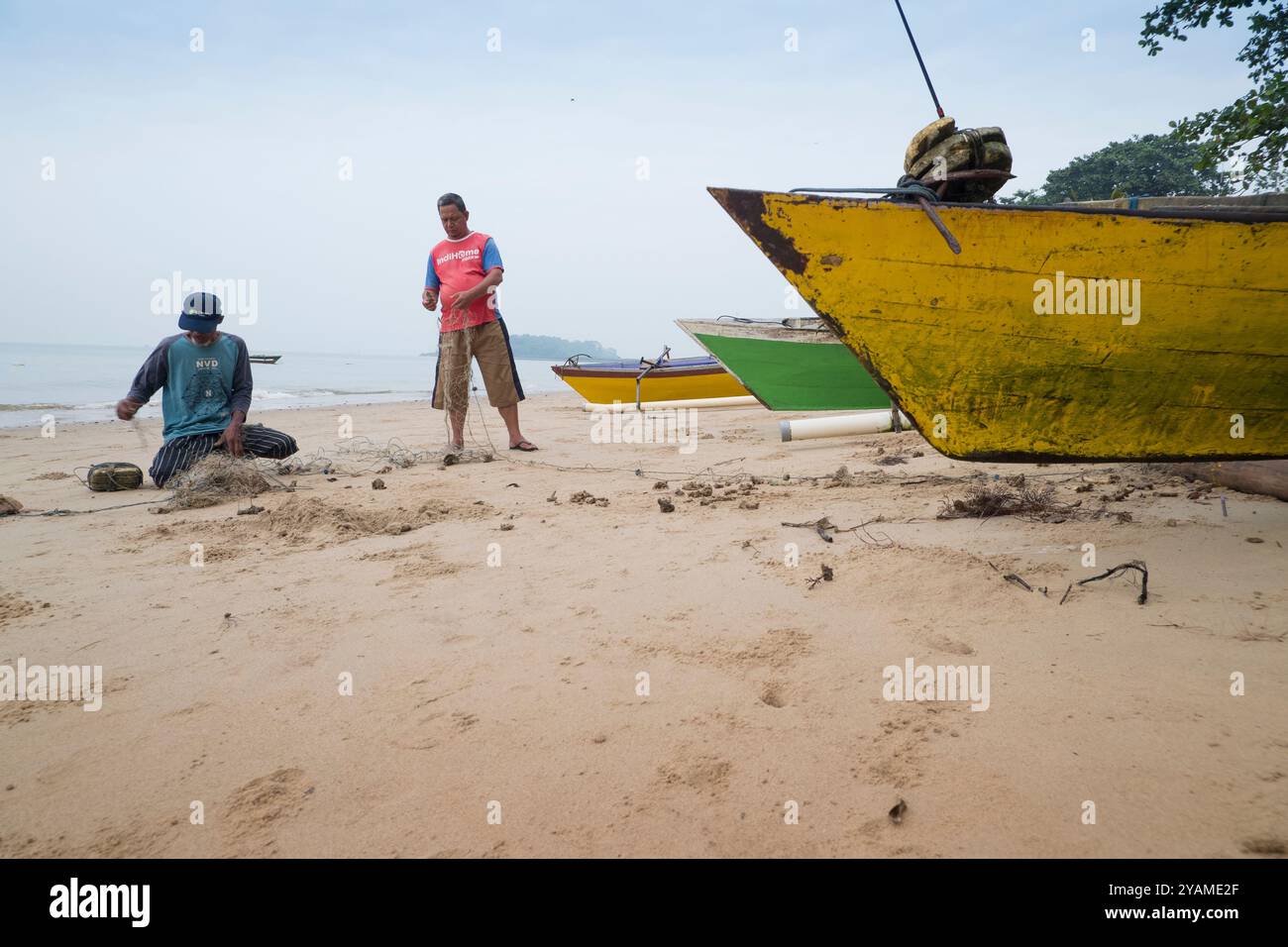 due pescatori stavano discutendo mentre spendevano le loro reti da pesca sulla spiaggia Foto Stock