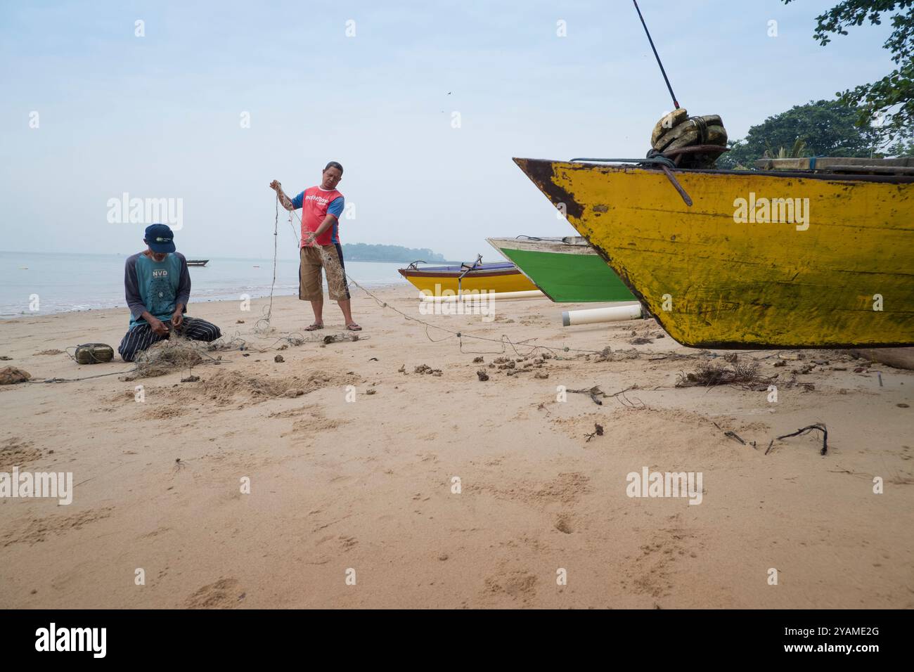due pescatori stavano discutendo mentre spendevano le loro reti da pesca sulla spiaggia Foto Stock