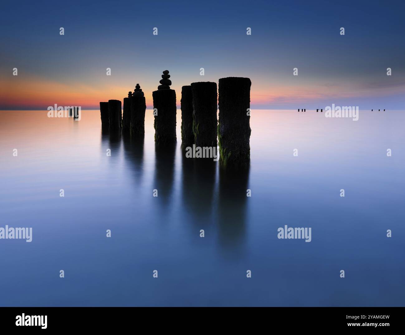 Piramidi di pietra su vecchi groynes con alghe in acqua sulla spiaggia del Mar Baltico, lunga esposizione al tramonto, Wustrow, Fischland-Darss-Zingst peninsu Foto Stock