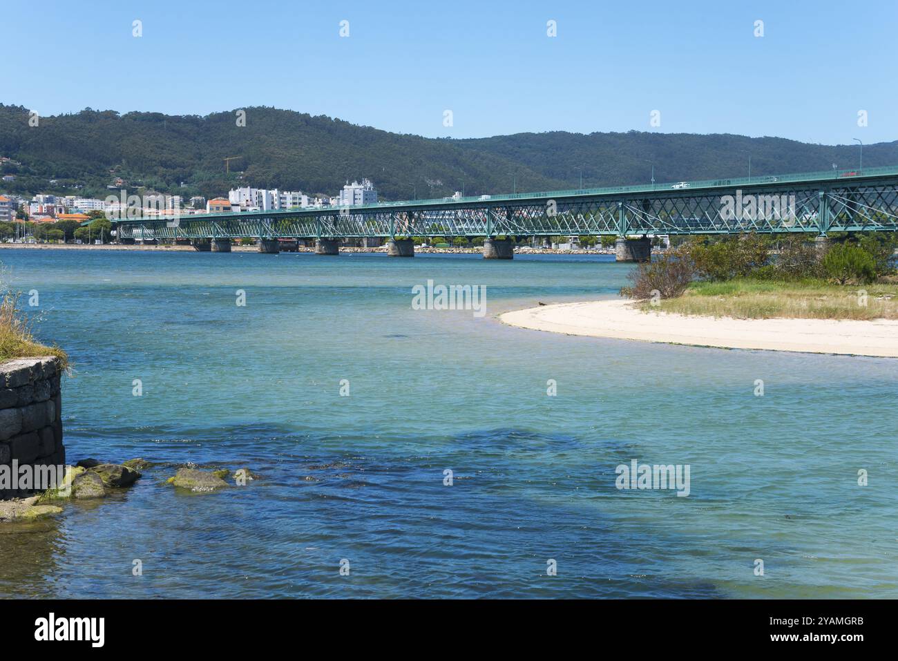Un lungo ponte attraversa un fiume blu scintillante, circondato da colline e una città sullo sfondo, Ponte Eiffel, Ponte di Gustave Eiffel, fiume Lima, V Foto Stock