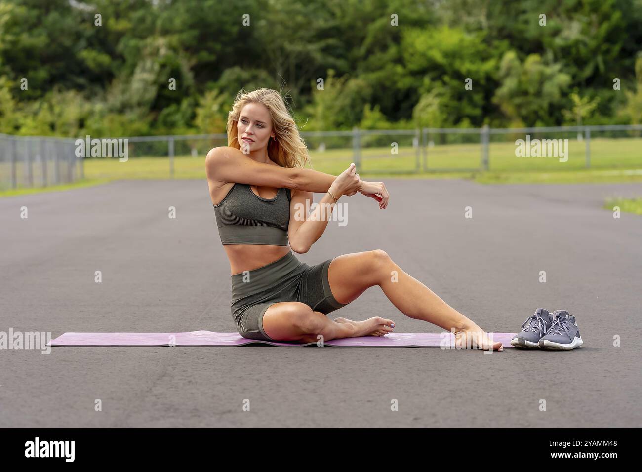 Un fantastico modello di fitness biondo si prepara per un allenamento, che irradia sicurezza e determinazione ad ogni mossa che fa Foto Stock