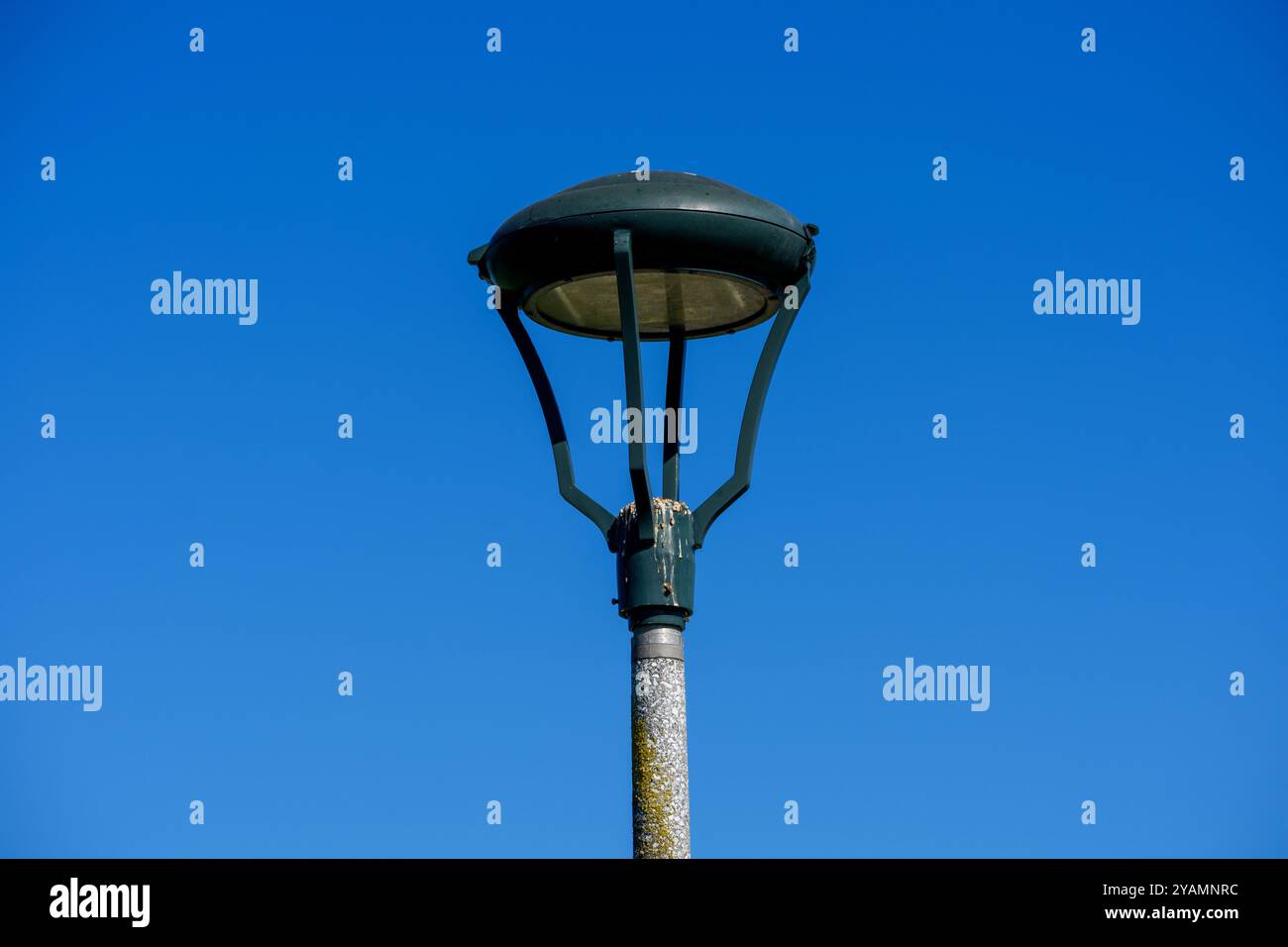 Un moderno lampione con un sistema di illuminazione a cupola si trova su un cielo blu brillante. Alla base del lampo sono visibili escrementi di uccelli e vernice intemprata Foto Stock