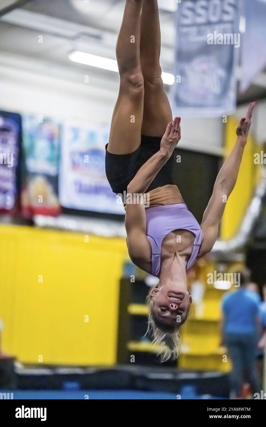 Una ginnasta dai colori vivaci perfeziona i suoi allenamenti in palestra prima di una gara, mostrando agilità, forza e grazia in ogni mossa Foto Stock