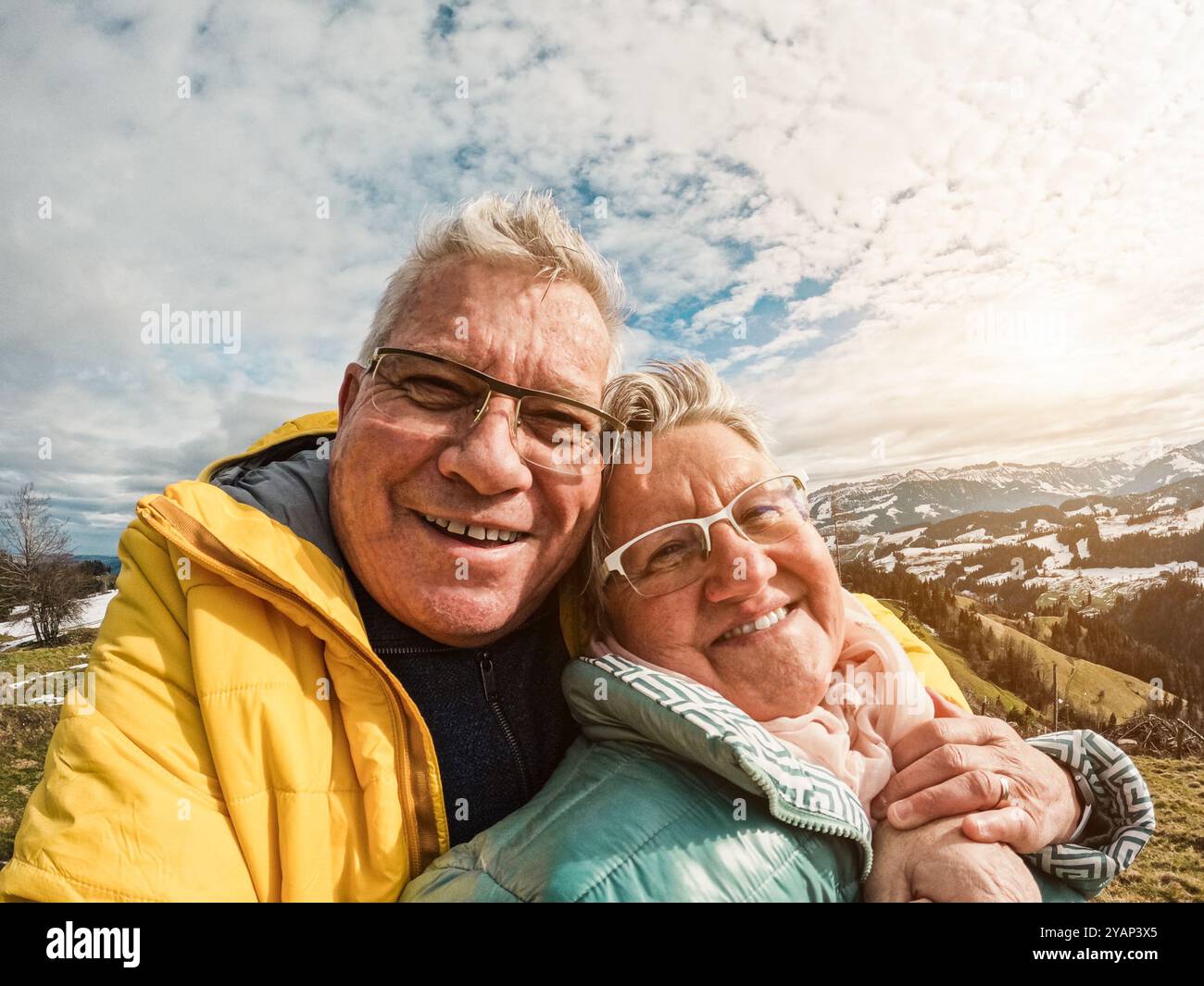 Felice coppia anziana che si prende selfie durante la giornata invernale di trekking in cima alla montagna - concetto di stile di vita per anziani con amore e gioia - concentrazione sui volti Foto Stock