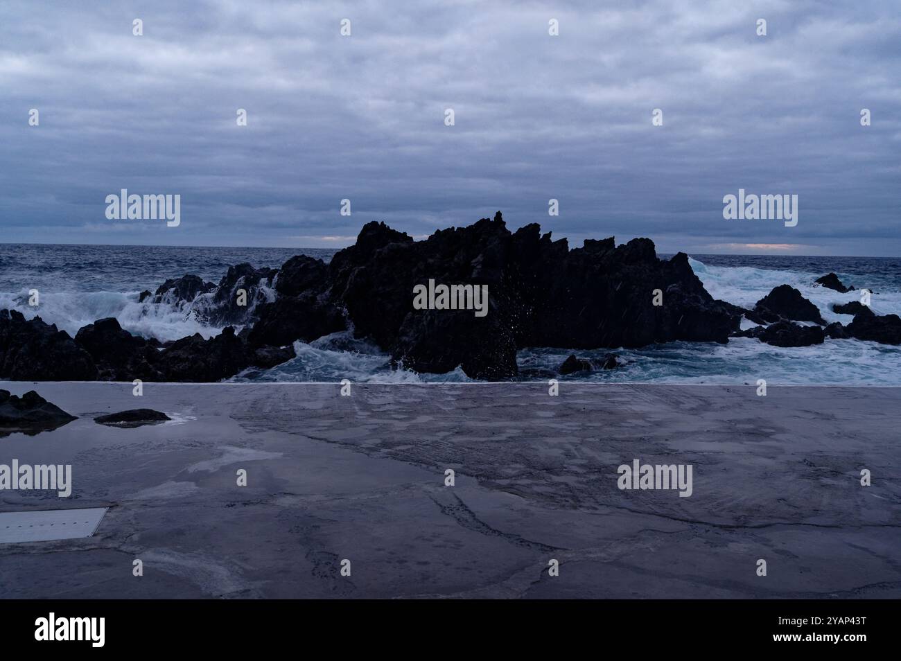 Le onde si infrangono contro le rocce vulcaniche sotto un cielo spettacolare nelle piscine naturali di Porto Moniz Foto Stock