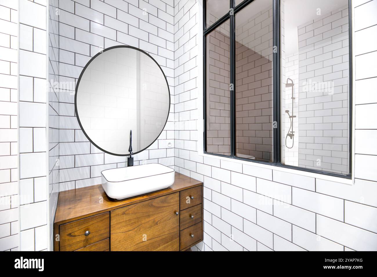 Bagno dal design moderno ed estetico con specchio circolare e elegante lavandino in legno Foto Stock