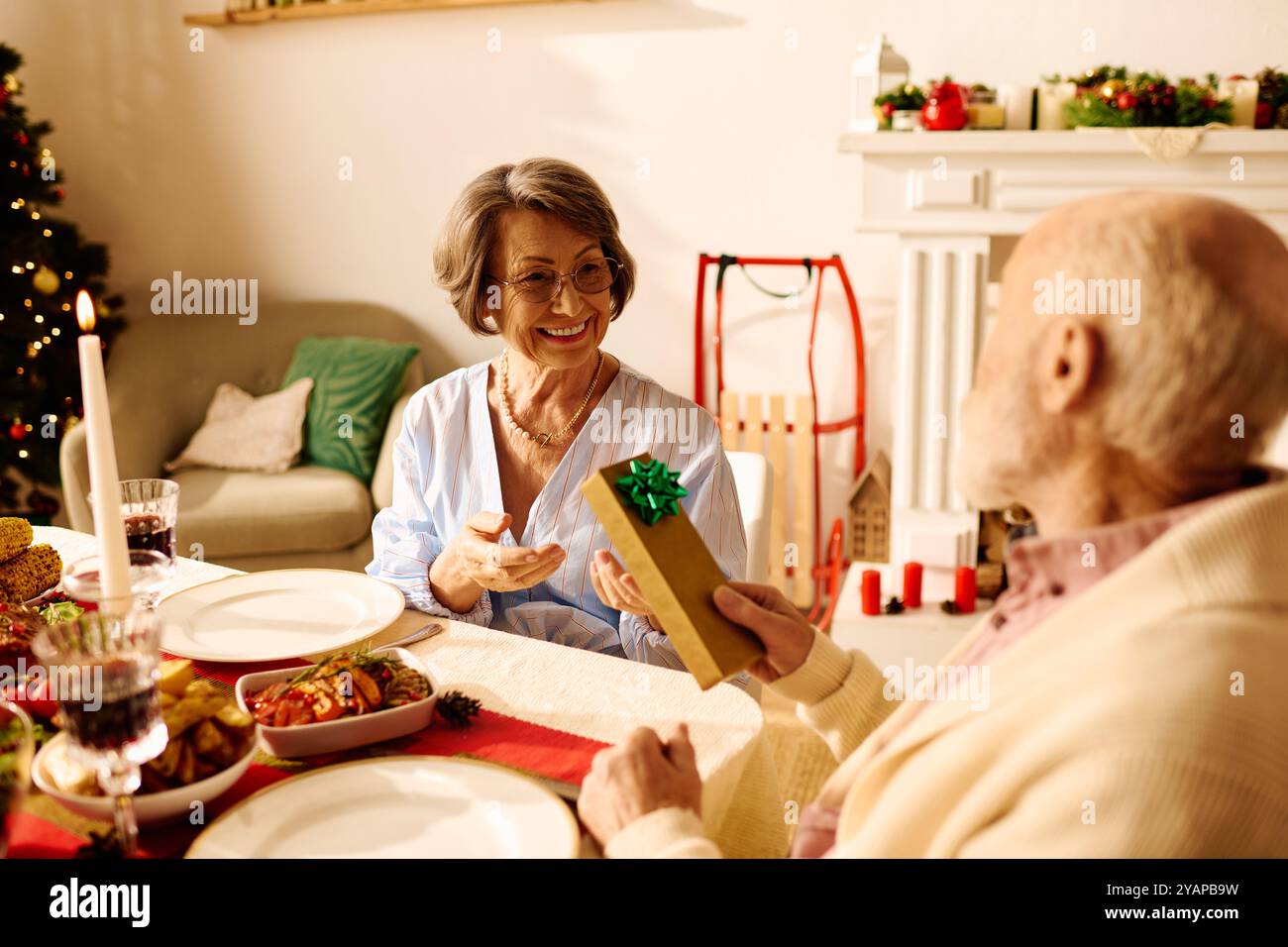 Una coppia condivide i regali in una casa accogliente e decorata durante le festività natalizie. Foto Stock