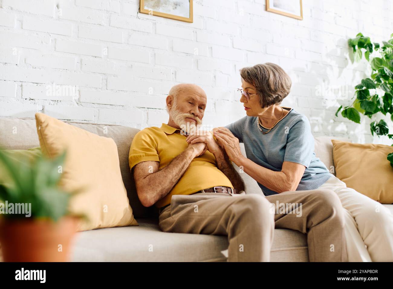 Una moglie devota assiste suo marito con il diabete, offrendo amore e sostegno nella loro casa. Foto Stock