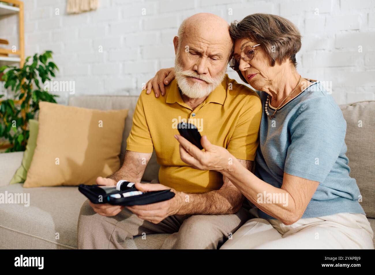 Una moglie devota aiuta suo marito a monitorare il suo diabete mentre si siedono comodamente insieme. Foto Stock