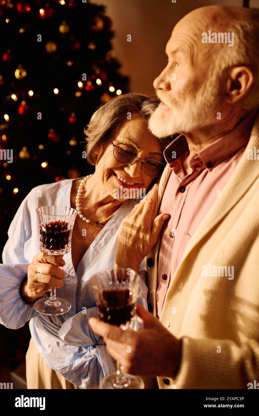 La coppia allegra si diverte a bere insieme, abbracciando il calore del Natale a casa. Foto Stock