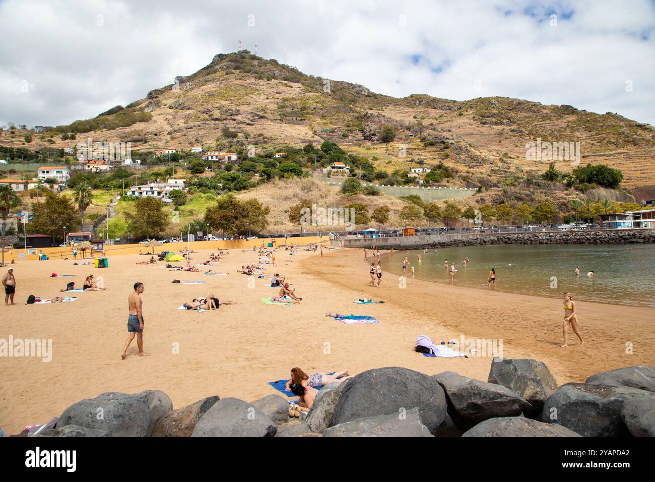 Turisti e persone che prendono il sole in vacanza sulla spiaggia artificiale di Machico, la seconda città/resort più grande dell'isola portoghese di Madeira Foto Stock