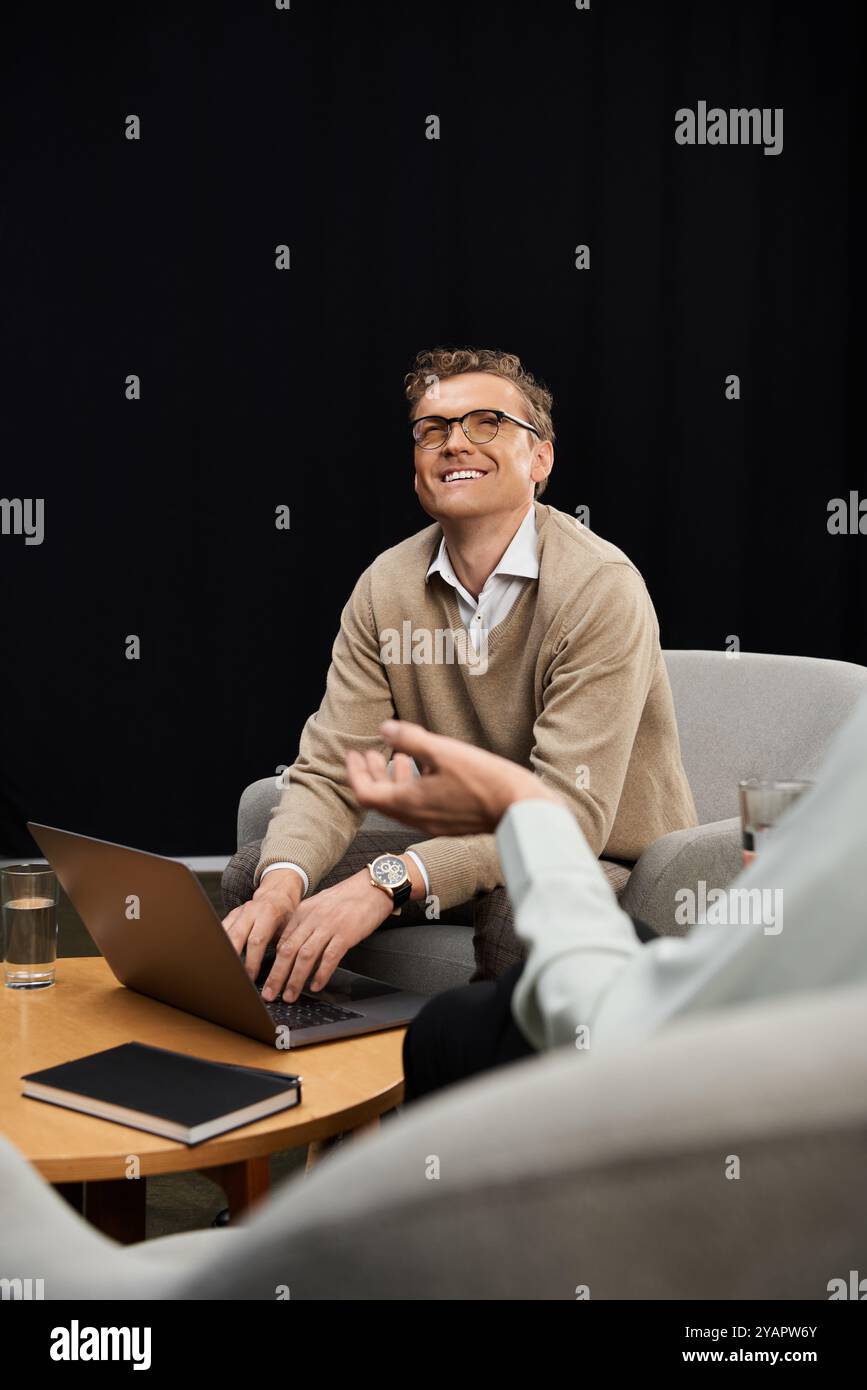 Un giornalista di mezza età intervista appassionatamente un esperto maschile in uno studio contemporaneo, catturando informazioni. Foto Stock