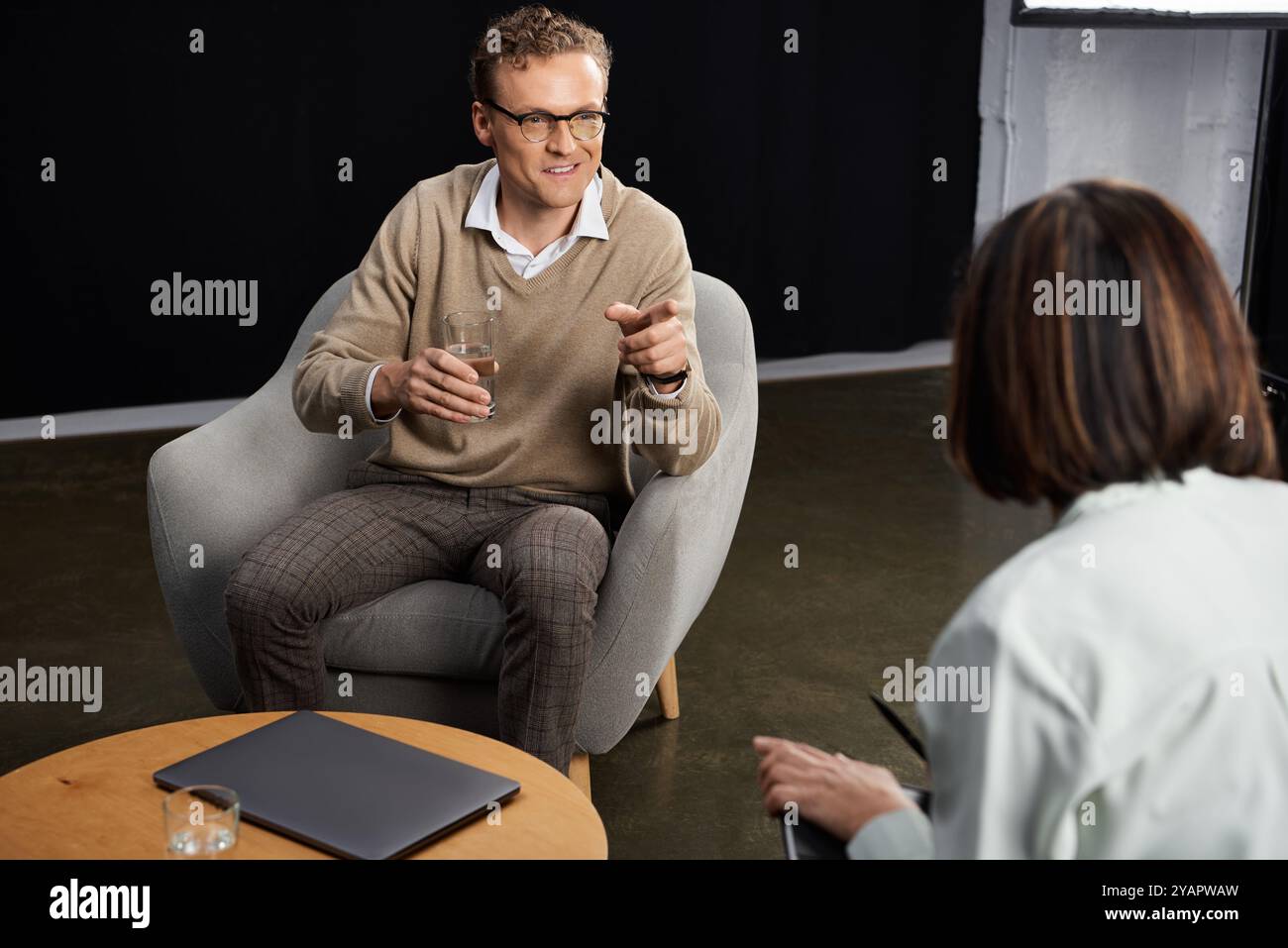 Un giornalista professionista parla con uno specialista, condividendo informazioni in un moderno ambiente di studio. Foto Stock