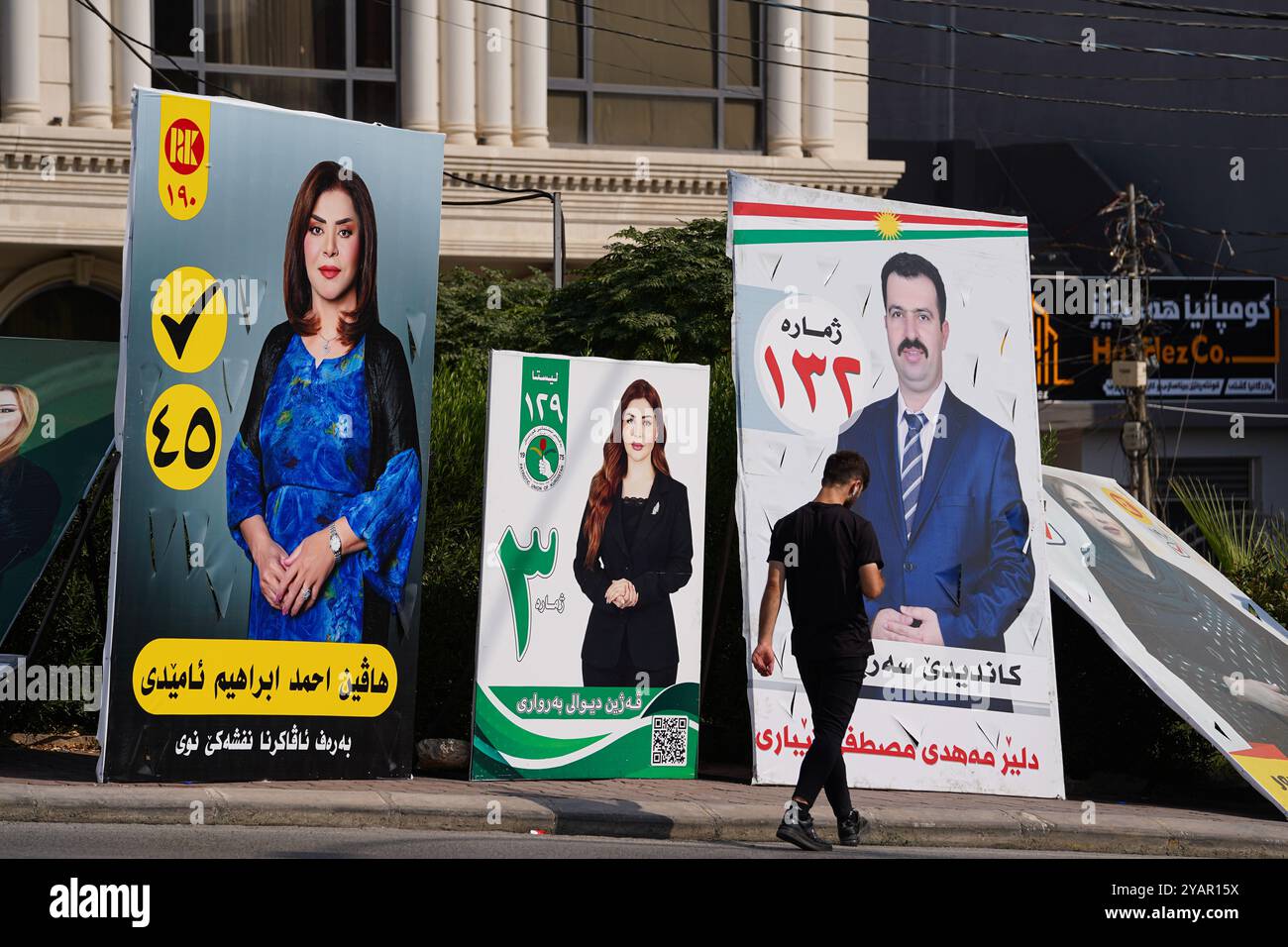 Duhok, Iraq. 13 ottobre 2024. Un giovane cammina lungo il lato della strada passando davanti alle bandiere elettorali del Partito Democratico del Kurdistan (KDP/PDK), del partito dell'Unione Patriottica del Kurdistan (PUK) e del candidato indipendente in vista delle elezioni del Parlamento regionale del Kurdistan nella città di Duhok, Iraq. (Foto di Ismael Adnan/SOPA Images/Sipa USA) credito: SIPA USA/Alamy Live News Foto Stock