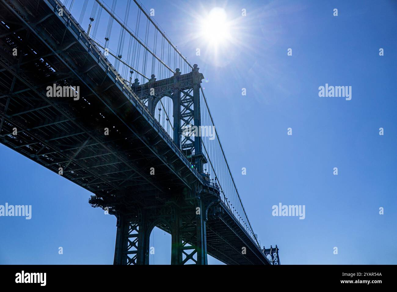 Vista ad angolo basso del ponte di Manhattan contro il sole e il cielo blu, New York City, New York, Stati Uniti Foto Stock