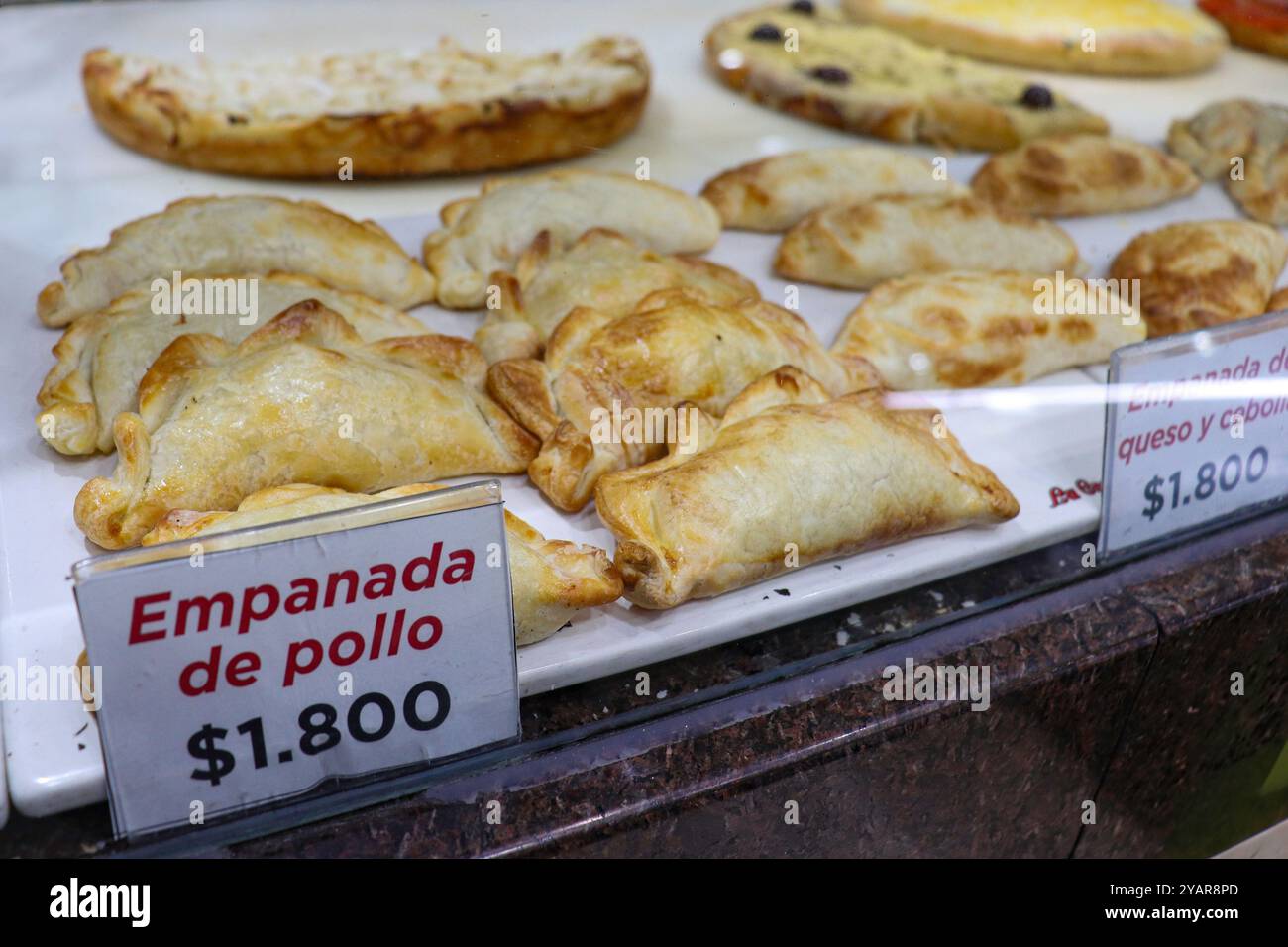 Empanada di pollo in una vetrina in una pizzeria con un cartello del prezzo Foto Stock