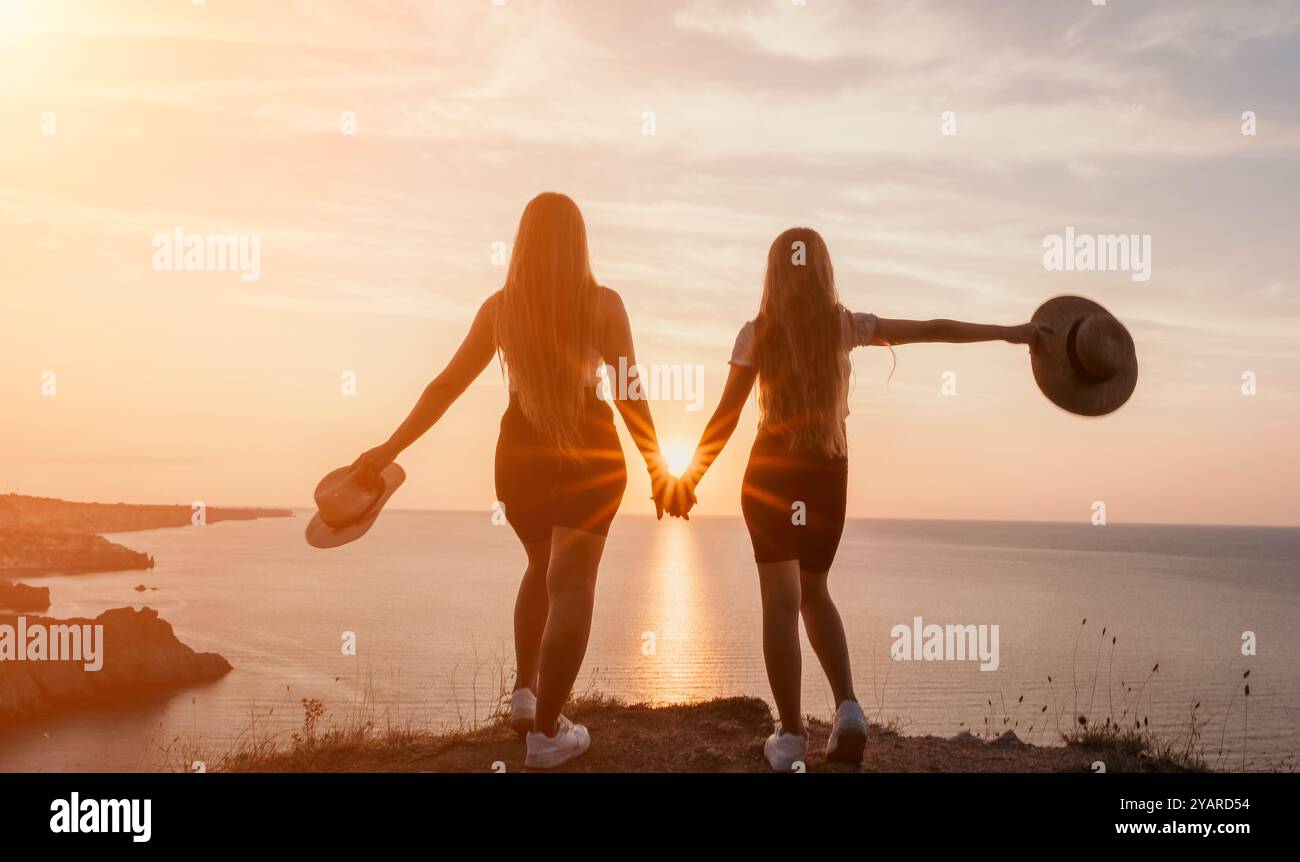 Silhouette di due donne che si tengono per mano al tramonto Foto Stock