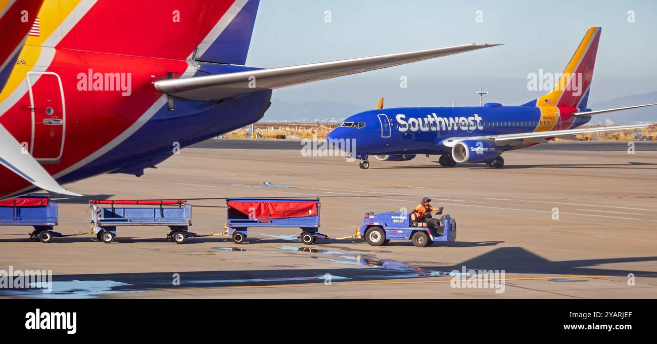 Oakland, California - Un operaio tira i carri bagge intorno agli aerei della Southwest Airlines all'aeroporto internazionale di Oakland (OAK). Foto Stock