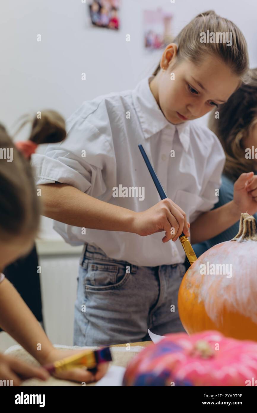 Bambini e adulti dipingono le zucche per Halloween, divertendosi e divertendosi insieme. Foto di alta qualità Foto Stock