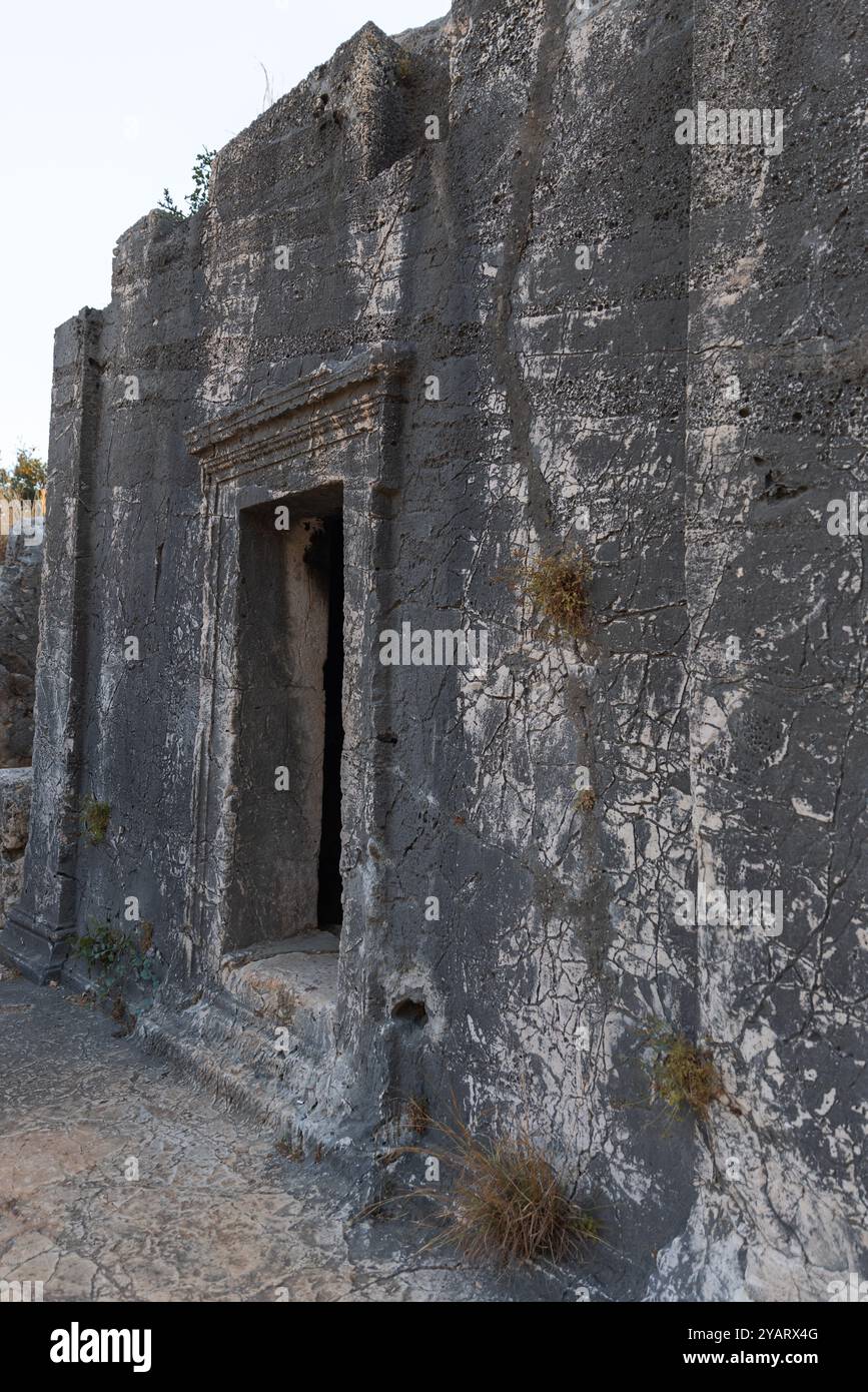 Muro di pietra scura della tomba dorica di Acdam nell'antica città di Antifello. Kas, Turchia Foto Stock