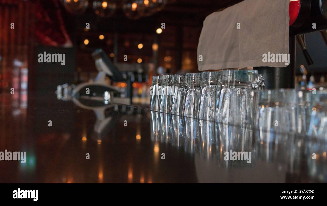 Bicchieri da shot vuoti di fila su un bancone di un bar all'interno di un nightclub. Fila di bicchieri da bibita collocati al bancone del bar. Foto Stock Bicchieri da shot vuoti di fila su un bancone di un bar all'interno di un nightclub. Fila di bicchieri da bibita collocati al bancone del bar. Foto Stock