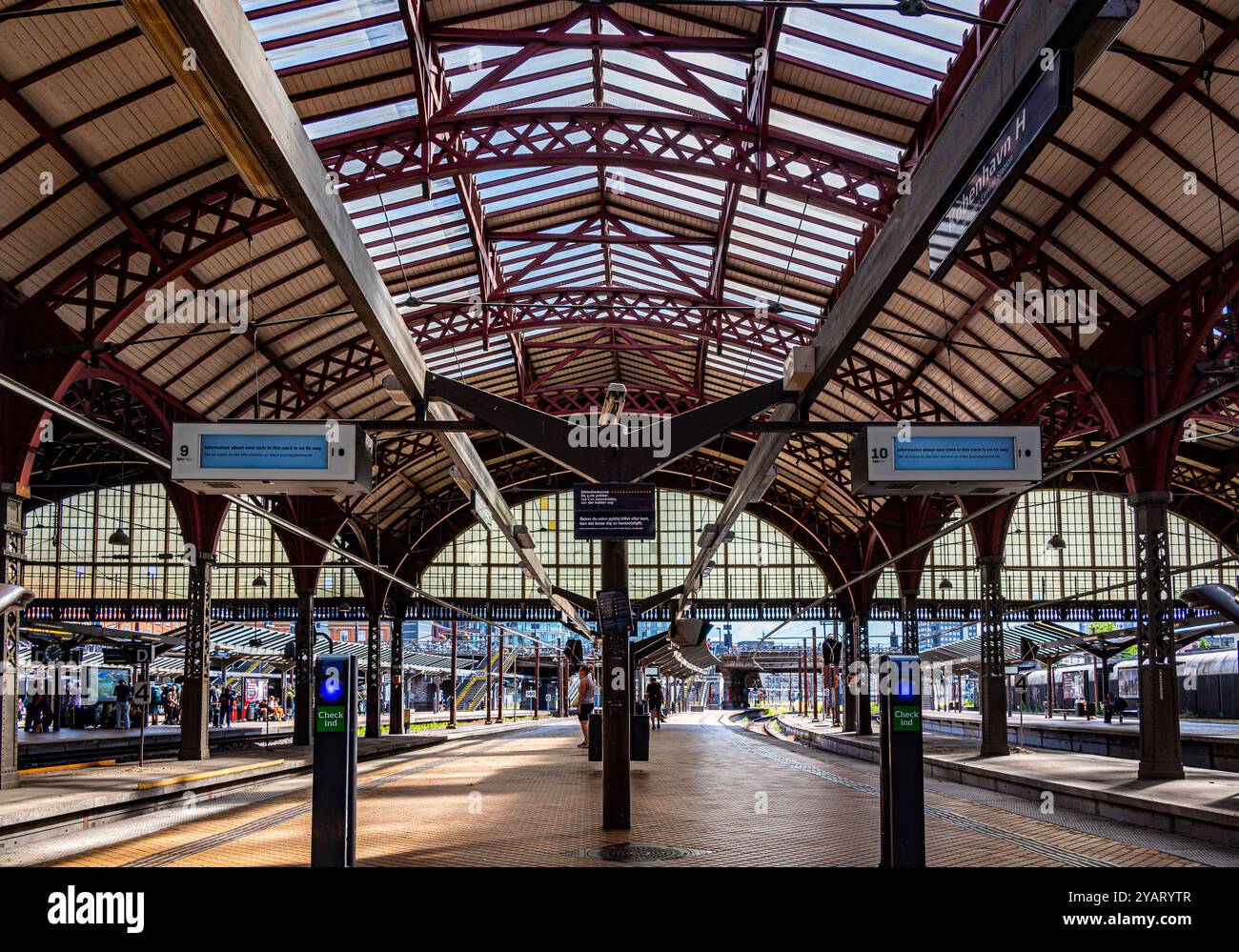 Piattaforme della stazione centrale di Copenaghen (København H) sotto il tipico tetto ad arco della ferrovia Foto Stock