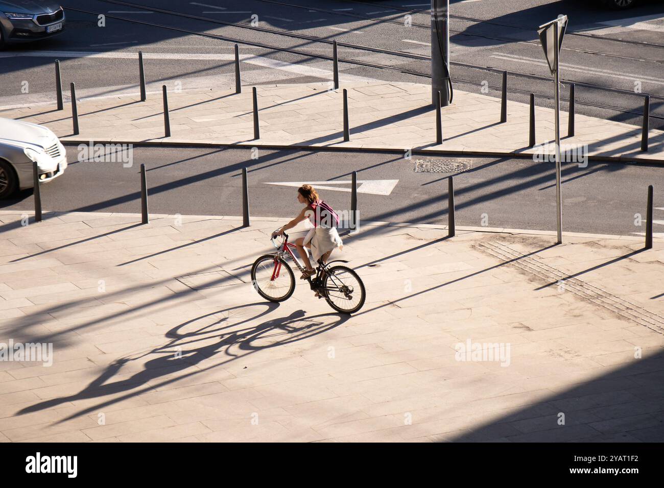 Belgrado, Serbia - 10 ottobre 2024: Donna in sella a una bicicletta sul marciapiede della città con cartelli stradali in una mattinata di sole Foto Stock