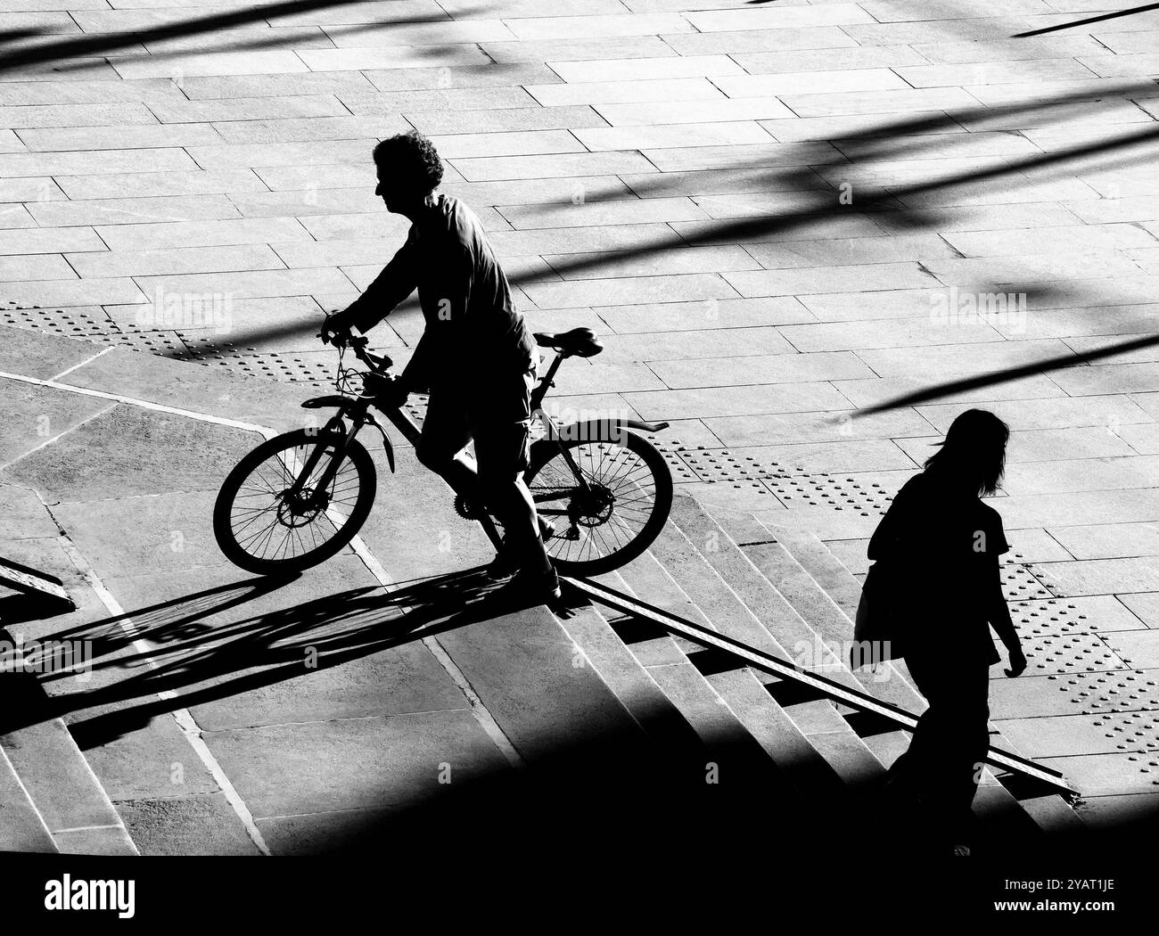 Belgrado, Serbia - 10 ottobre 2024: Sagoma omata di una persona che spinge su una bicicletta su una scala ciclabile rampa di corsa e donna che cammina giù, in alto Foto Stock