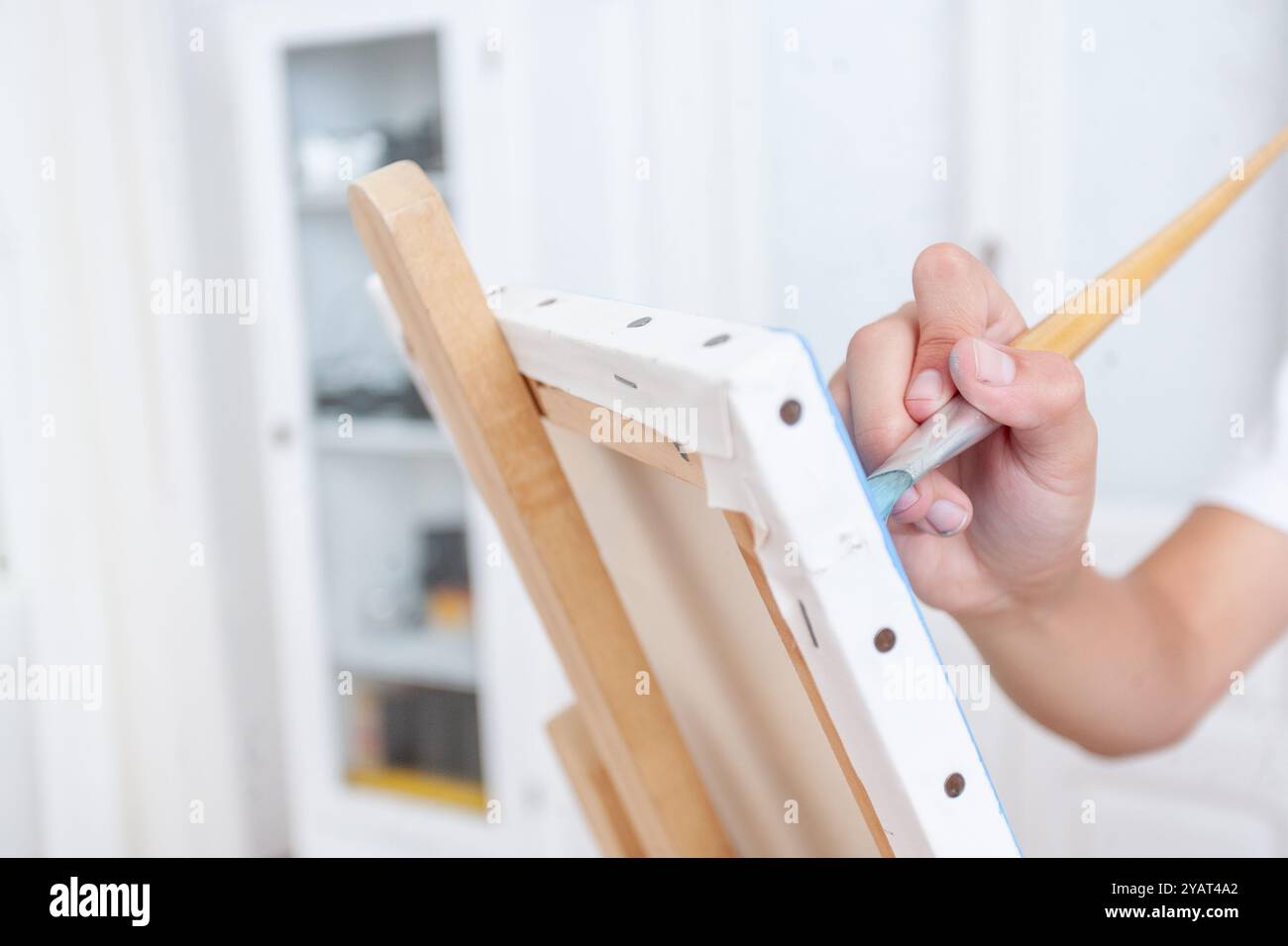 Una persona sta dipingendo un'immagine su una tela con un pennello. Il dipinto è in corso e la persona è concentrata sul suo lavoro Foto Stock