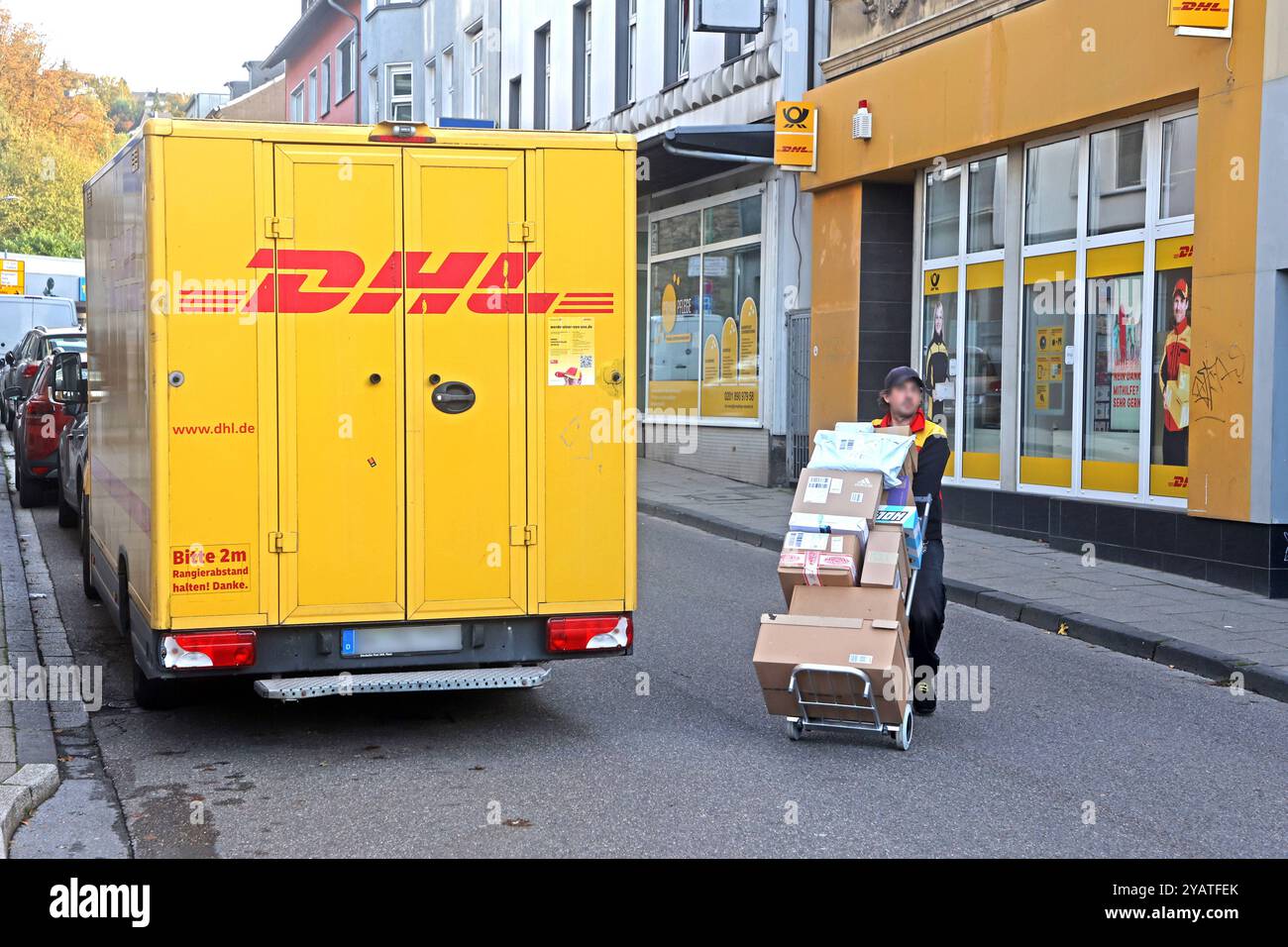 Zustelldienst auf den Straßen Ein Paketdienst des Unternehmens DHL fährt mit seiner Fracht durch die Nebenstraßen und hält vor einer filiale der Deutschen Post um zahlreiche Pakete zu liefern Essen Nordrhein-Westfalen Deutschland *** servizio di consegna per le strade Un servizio pacchi DHL attraversa le strade laterali con il suo carico e ferma di fronte a una filiale Deutsche Post per consegnare numerosi pacchi Germania-Essen-Westphen Foto Stock