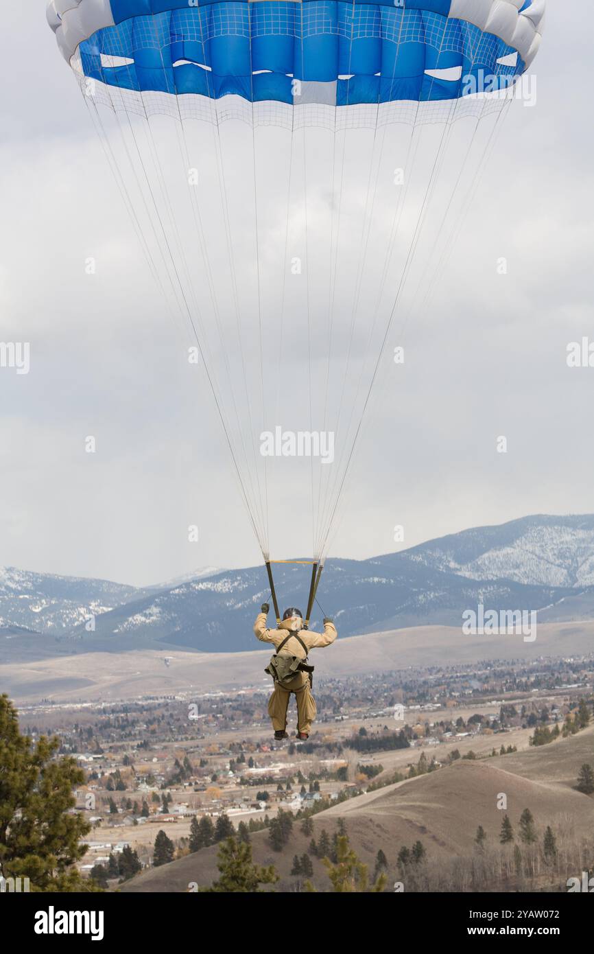 Uno Smokejumper del servizio forestale scende verso la zona di atterraggio con un salto di prova, la valle di Missoula è visibile sullo sfondo, MT. Foto Stock