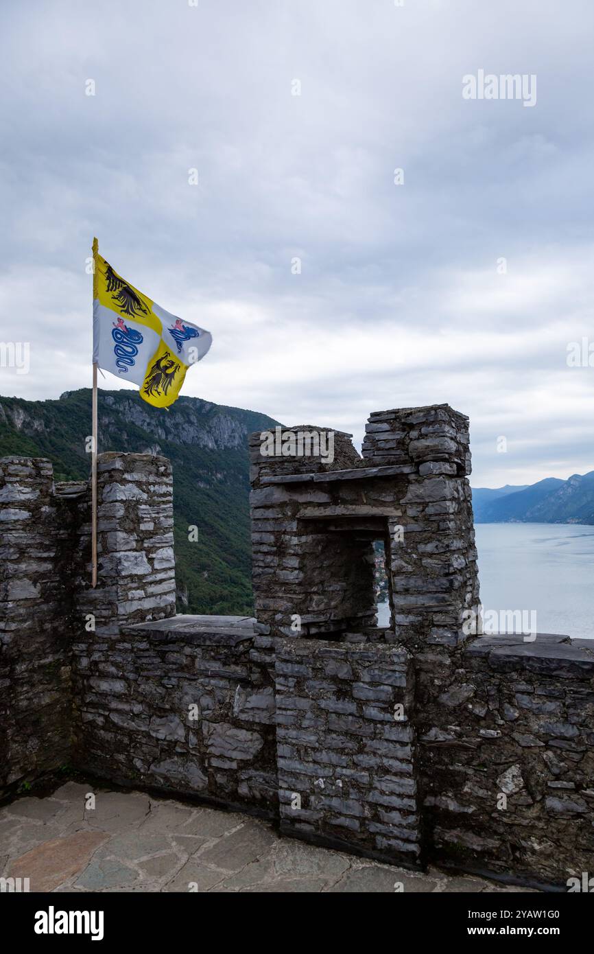 La bandiera del Ducato di Milano sorvola il Castello di Vezio con il Lago di Como a Perledo, Lombardia, Italia. Foto Stock