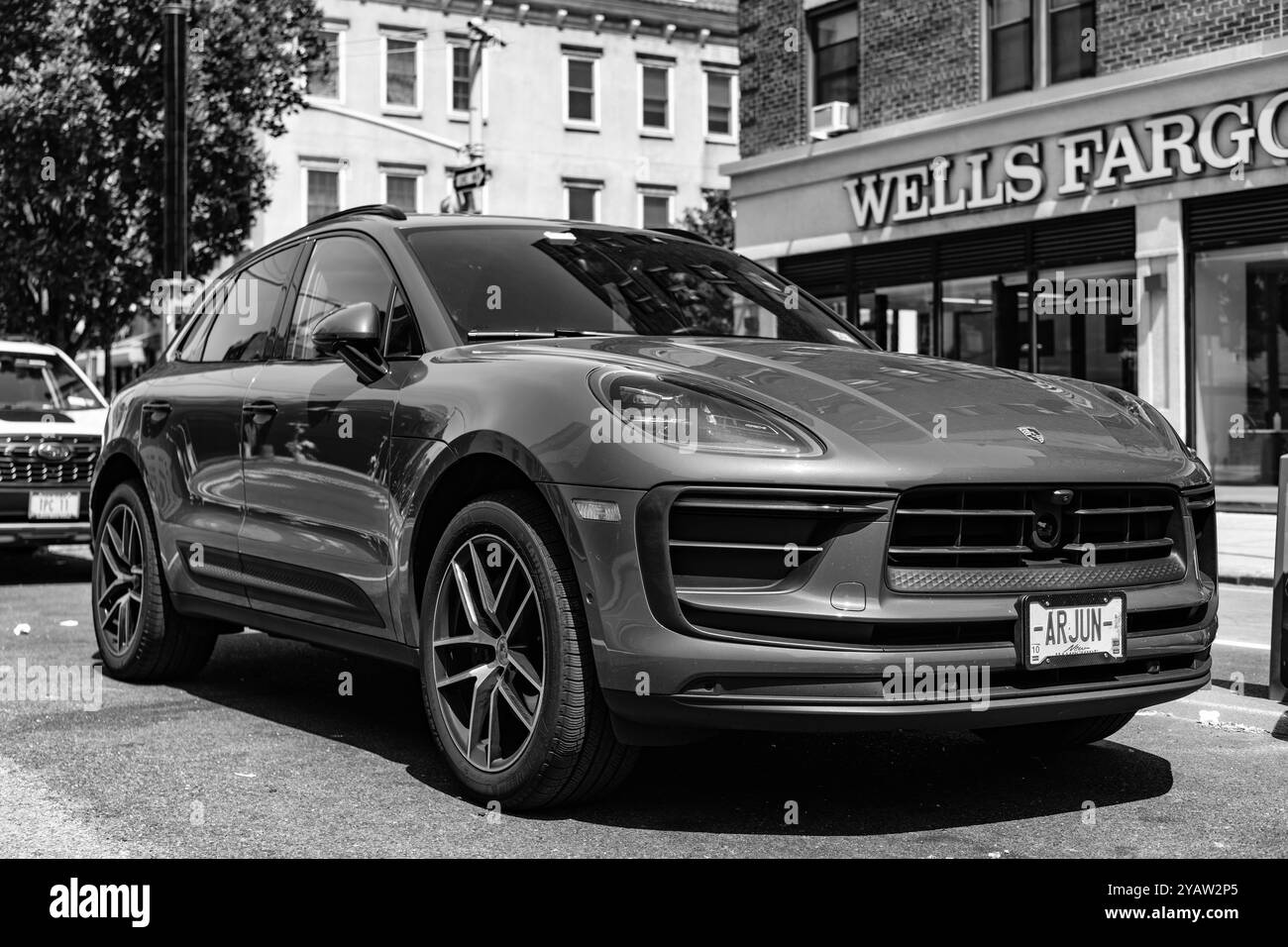 New York City, USA - 5 agosto 2023: 2023 Porsche Macan T SUV Ruby Red, vista frontale e laterale, parcheggio sul lato sinistro della strada Foto Stock